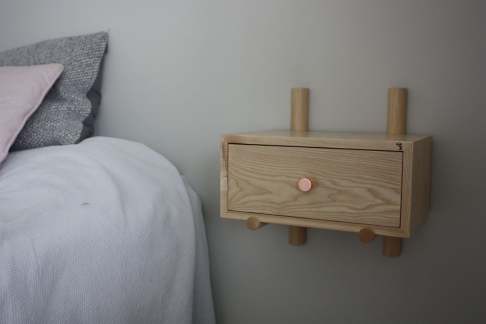 Pieni puinen yöpöytä kiinnitettynä seinään