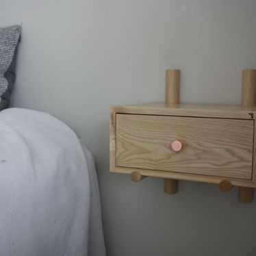 Pieni puinen yöpöytä kiinnitettynä seinään